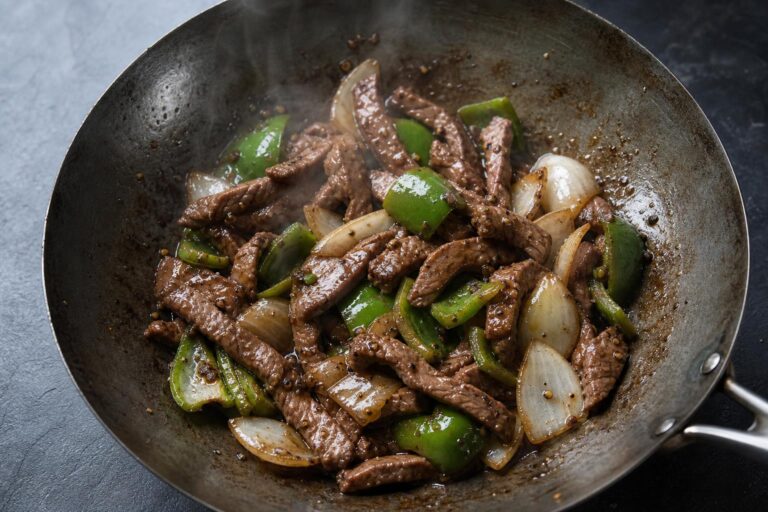 Black pepper beef stir fry with onions and green peppers in a carbon steel wok