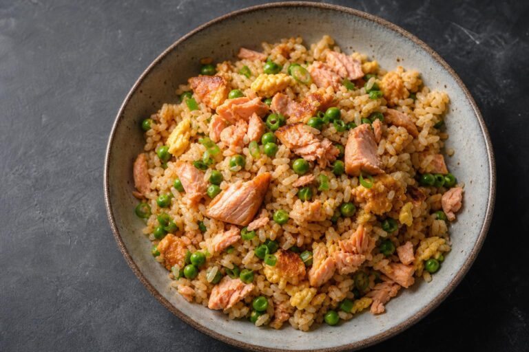Salmon fried rice with egg, peas, and scallions in a ceramic bowl