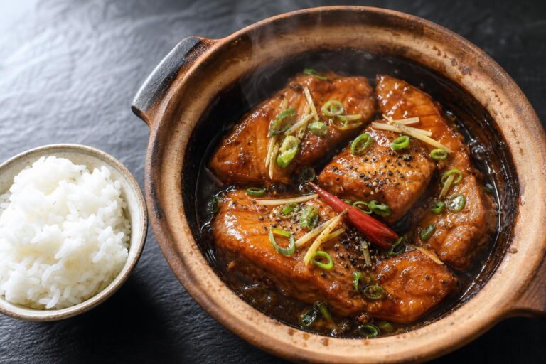 Vietnamese caramel salmon braised in a clay pot with ginger, green onion, and black pepper, served with steamed rice