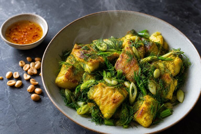 Overhead bowl of Vietnamese turmeric dill fish with dill, scallions, peanuts and fish sauce