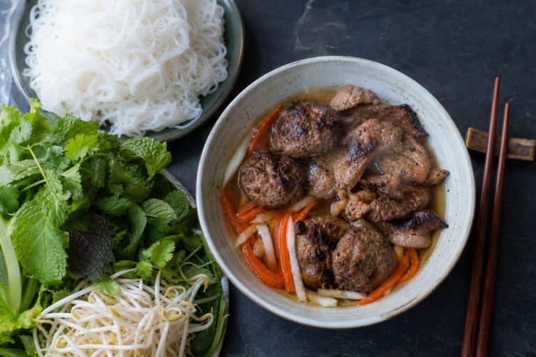 Overhead bowl of Vietnamese bun cha, grilled pork patties and slices in nuoc cham with vermicelli and herbs